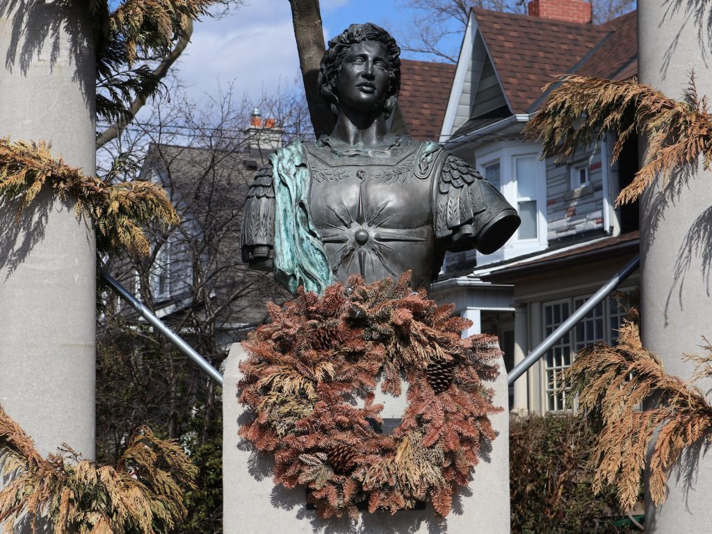 a statue of a woman with a wreath in front of a house